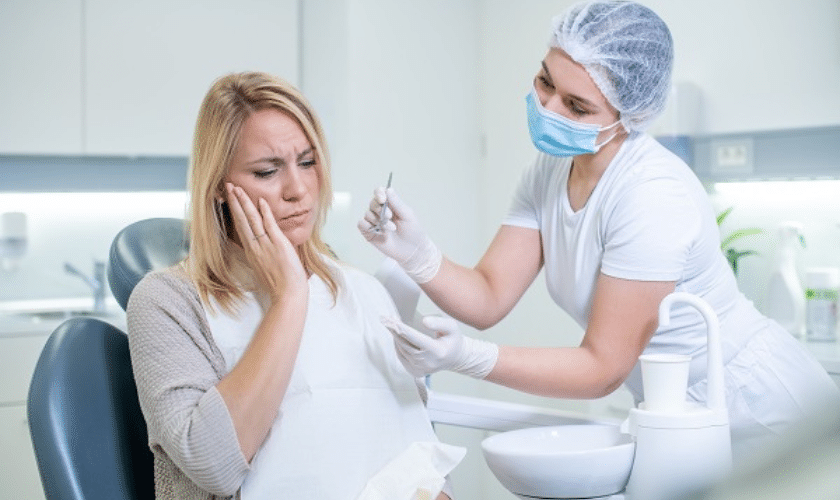 A woman with a toothache seeks help from an emergency dentist near her at an emergency dental near her.