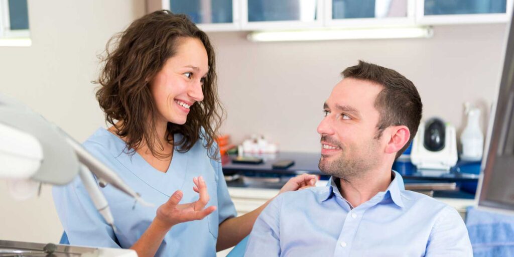 A happy patient discusses treatment options with an emergency dentist near him at a clinic of emergency dental near him.