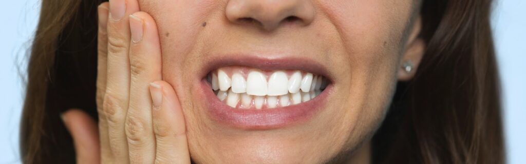 Woman experiencing gum pain, indicating a need for periodontics, gingivitis treatment, or gum disease care.
