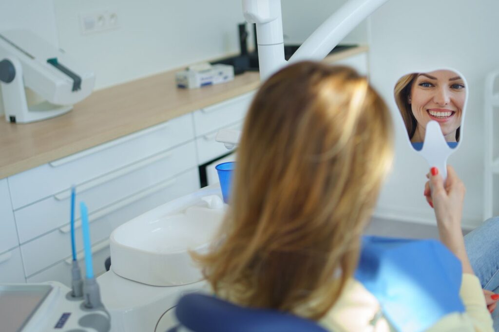 A lady sees herself in a mirror after getting oral and maxillofacial surgery at the dental oral surgeon near Johns Creek and Arbor Trace.