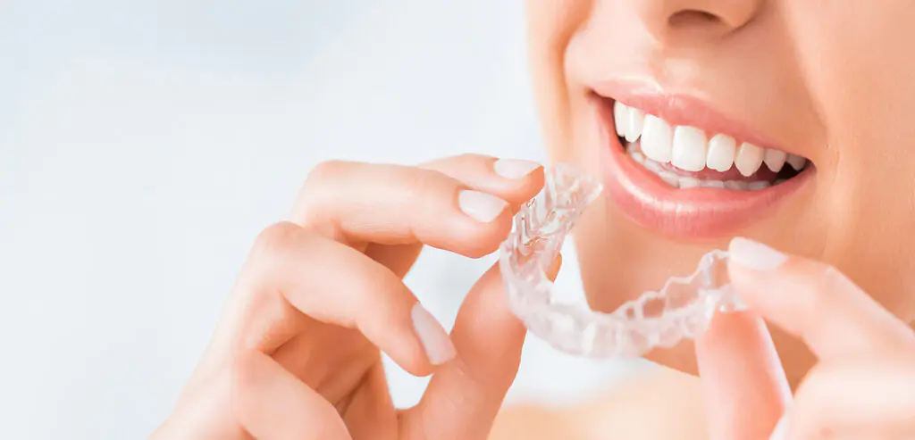 A beautiful woman wearing Invisalign aligners at the Invisalign dentist’s office.